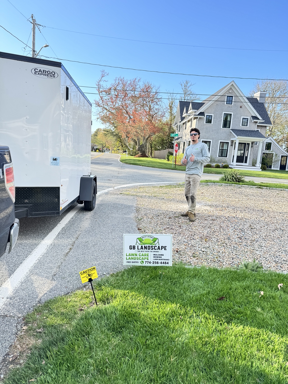 GB Landscape crew member beside company yard sign