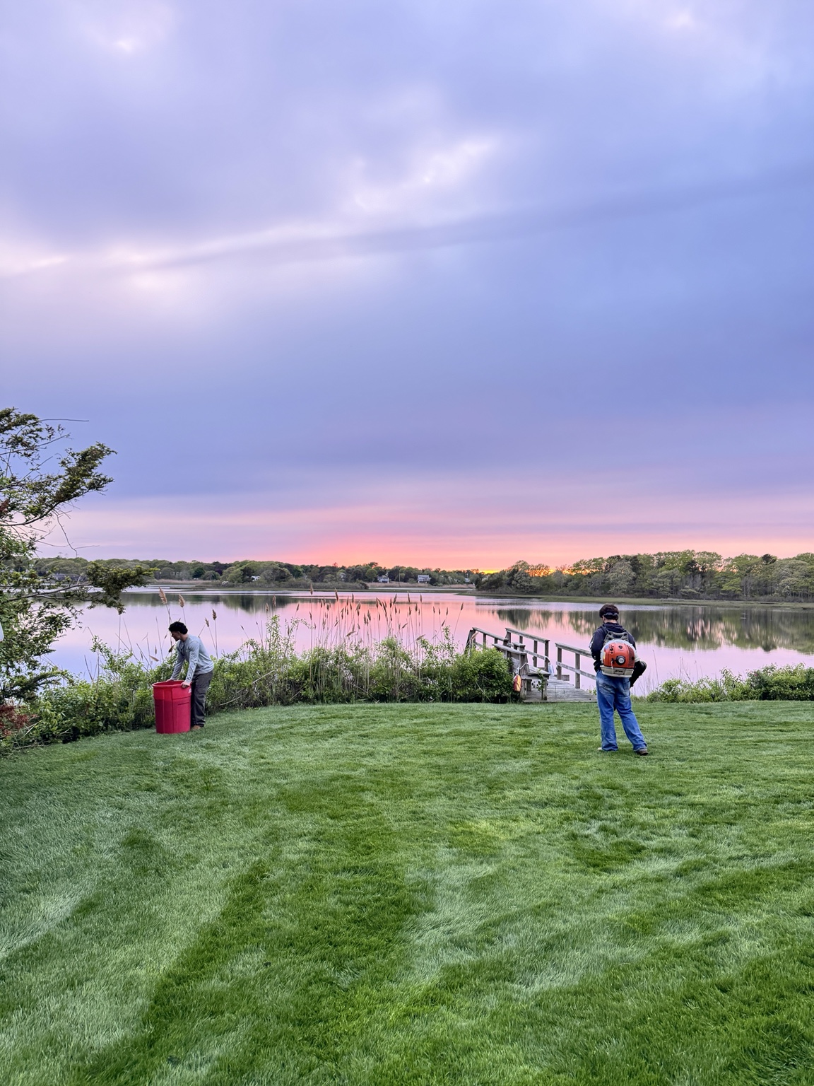 GB Landscape crew maintaining a waterfront lawn at sunset